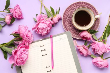 Boş defterli kompozisyon, bir fincan kahve ve leylak arka planda güzel şakayık çiçekleri.