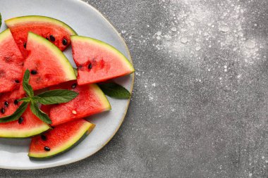 Taze karpuz parçaları ve gri arkaplanda nane.