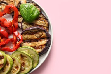 Pembe arka planda lezzetli ızgara sebzeli tabak.