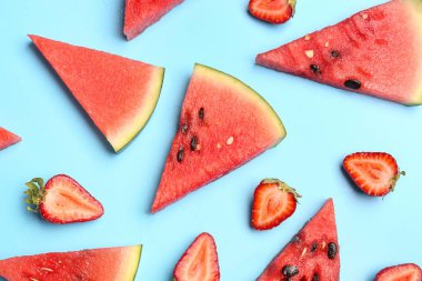 Taze karpuz parçaları ve mavi arka planda çilekler.