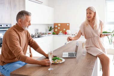 Olgun bir çift mutfakta yemek yiyor.