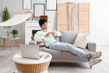 Asyalı genç adam izin gününde cep telefonu kullanıyor.