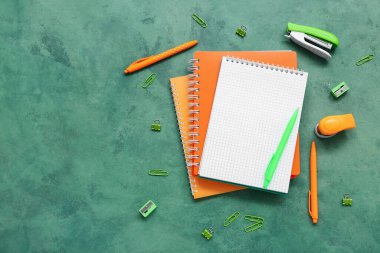 Boş defter ve grunge yeşil arkaplan üzerindeki farklı kırtasiye