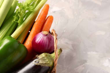 Arka planda farklı taze sebzeler olan hasır sepet, yakın plan.