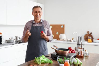 Mutfakta taze domatesli olgun bir adam.