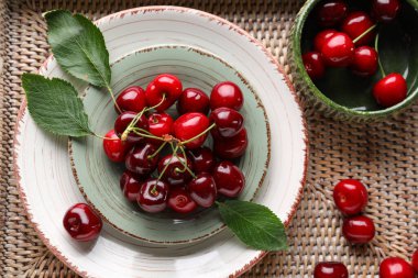 Hasır tepside tatlı kirazlı tabak ve kase, yakın plan.