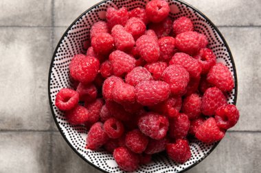 Gri fayans masasında taze ahududu kasesi.