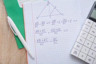 Hesap defterini formüller, hesap makinesi ve kalemle ahşap masa üzerinde aç