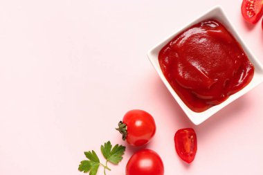 Domates ezmeli kase ve pembe arka planda taze sebzeler.