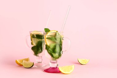 Pembe arka planda soğuk mojito ve turunçgil meyveleri.