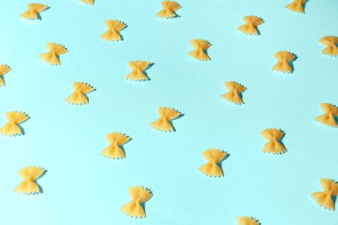 Mavi arka planda pişirilmemiş farfalle makarna kompozisyonu
