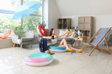 Plaj aksesuarlarıyla evde selfie çeken genç bir kadın.