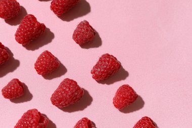 Pembe arka planda bir sürü taze ahududu