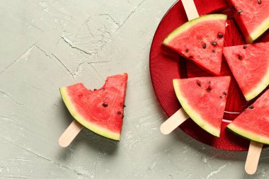 Gri zemin üzerinde tatlı karpuz çubukları olan bir tabak.