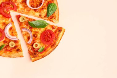 Zeytinli, domatesli ve bej arka planda fesleğenli lezzetli pizza.