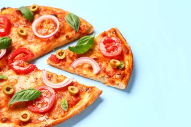 Zeytinli, domatesli ve mavi arka planda fesleğenli lezzetli pizza.