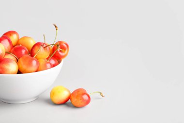 Gri arka planda tatlı sarı kirazlı kase