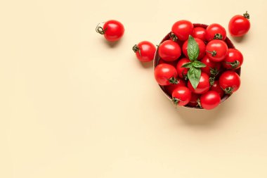 Taze kiraz domatesli kase ve turuncu arka planda fesleğen.