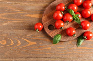 Taze vişneli domates ve ahşap masada fesleğen.