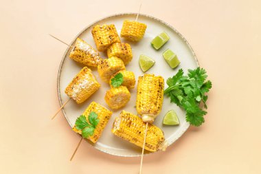 Lezzetli ızgara mısır koçanı ve sarı arka planda maydanozlu tabak.