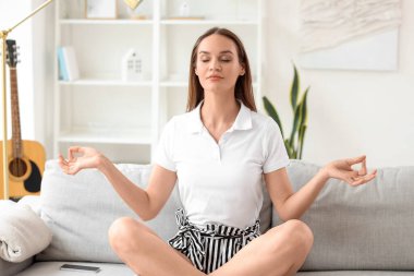 Genç bir kadın izin gününde evde meditasyon yapıyor.