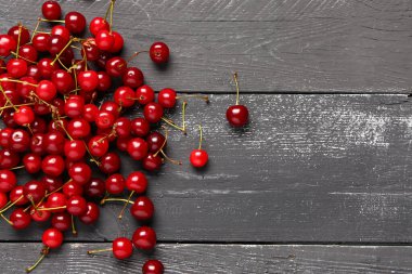 Siyah ahşap arka planda kırmızı kiraz yığını