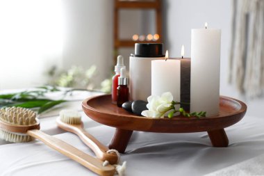 Spa composition with burning candles on couch in salon, closeup