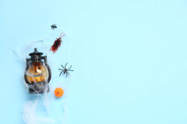 Mavi arka planda şeker böcekleri, fener ve ağ ile Cadılar Bayramı kompozisyonu