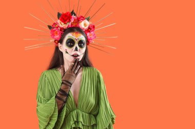 Turuncu arka planda Cadılar Bayramı için giyinmiş genç bir kadın.