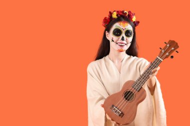 Cadılar Bayramı için giyinmiş, turuncu arka planda gitarı olan güzel bir kadın.