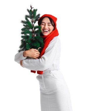 Beyaz arka planda Noel ağacı olan kalın elbiseli genç bir kadın.