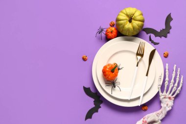 Kabaklı masa ayarları ve mor arkaplanda Cadılar Bayramı dekorasyonu