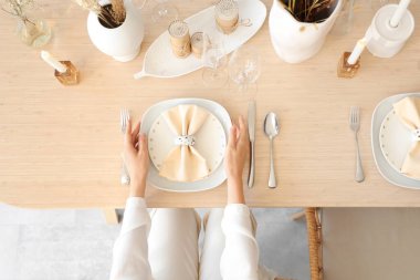 Kadın elleri yemek odasında masayı hazırlıyor, yakın plan.