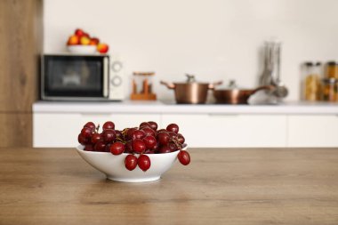 Modern mutfaktaki ahşap masada taze kırmızı üzümlü kase.