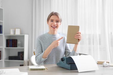 Ofisteki kitaba işaret eden klasik daktiloyla kadın yazar