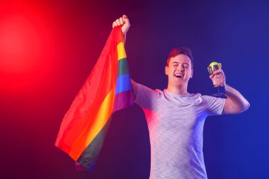 Koyu arkaplanda altın kupa ve LGBT bayrağı taşıyan erkek tenisçi