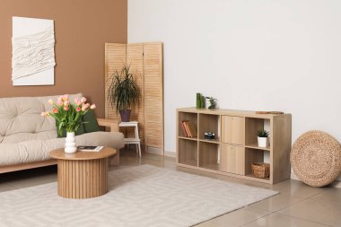 Kanepesi, çekmecesi ve 3 boyutlu tekstil sanatı olan modern oturma odasının içinde.