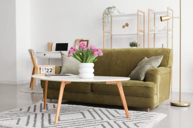 İçinde lale, dergi ve takvim olan vazo şık oturma odasının iç tarafında.