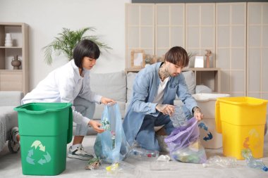 Evlerinde çöp kutularını düzenleyen genç bir çift. Geri dönüşüm kavramı