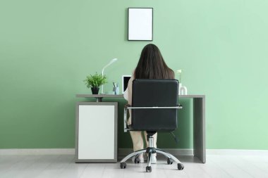 Yeşil ofisteki şık işyerinde modern laptopla çalışan genç bir kadın.