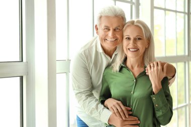 Olgun bir adam, evinde evlilik yıldönümlerinde karısına sarılıyor.