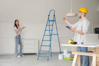 Erkek müteahhit odada müşteri onarımı yapıyor.