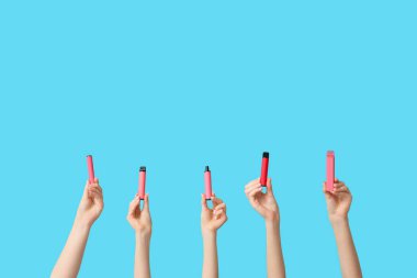 Mavi arka planda elektronik sigara tutan bir sürü el var.