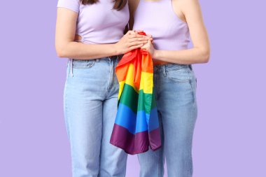Leylak arka planında LGBT bayrağı olan genç lezbiyen çift
