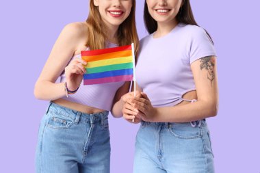 Leylak arka planında LGBT bayrağı olan genç lezbiyen çift