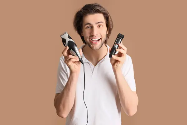 stock image Young bearded man with trimmers on brown background