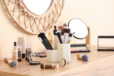 Makyaj fırçaları ve farklı dekoratif kozmetik ürünleri olan tutucu.