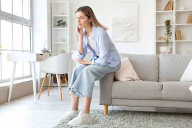 Evde diş ağrısı çeken genç bir kadın.