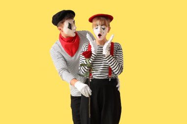 Sarı arka planda gül olan bir çift pandomist.