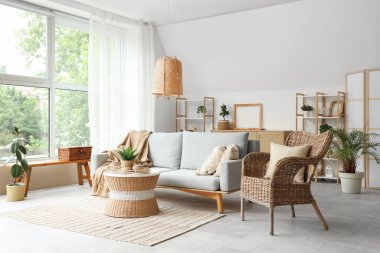 Hasır sepeti, sandalyesi ve masası olan şık bir oturma odası.